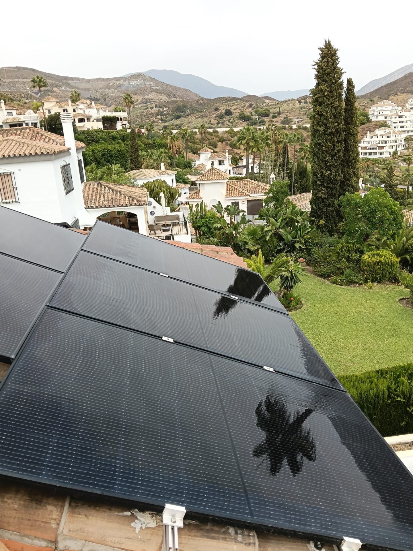 Large solar array on a hillside villa in the Costa del Sol, partially shaded by a palm tree