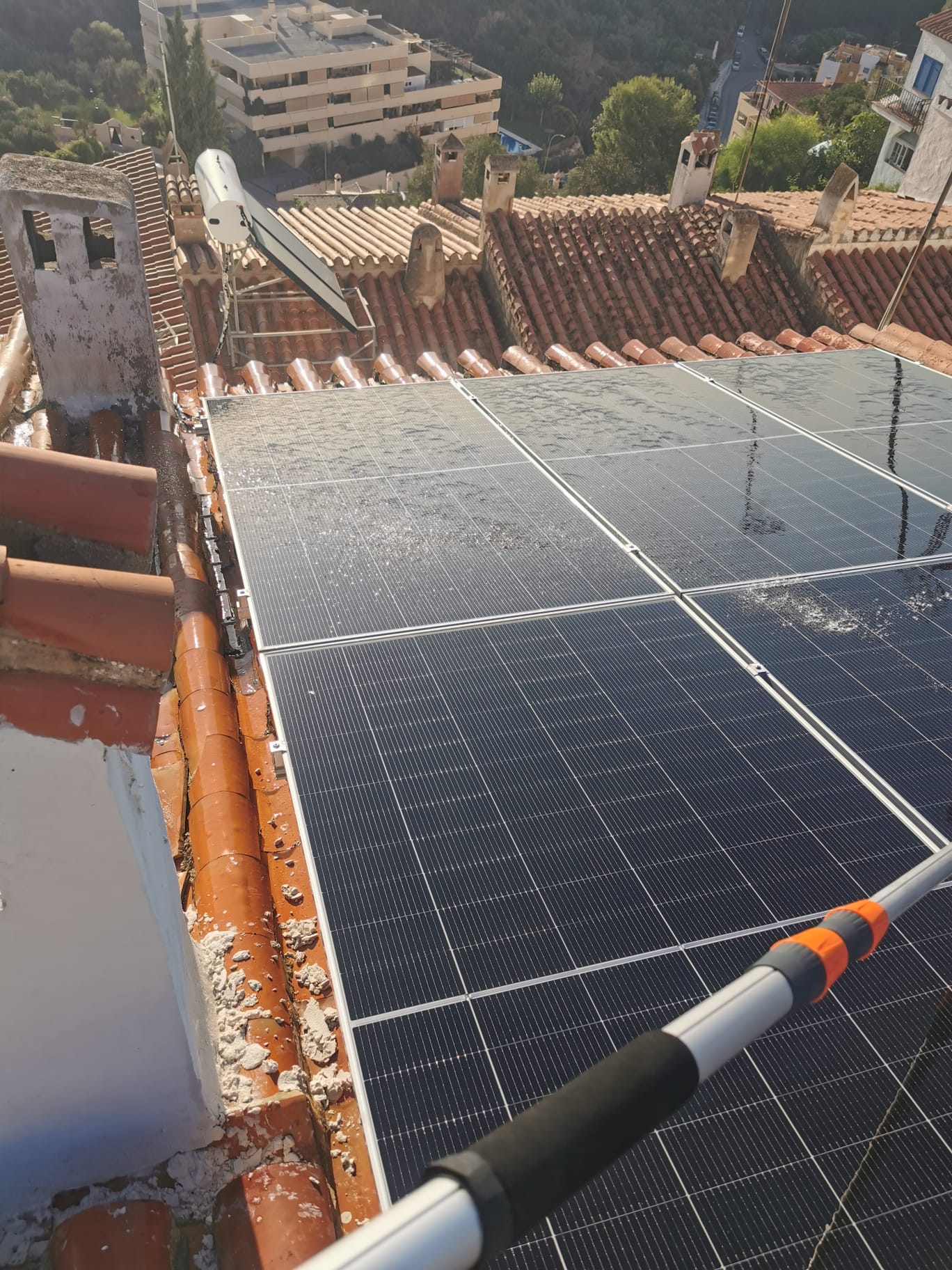 Solar panel cleaning in progress with telescopic brush, Vélez-Málaga rooftop