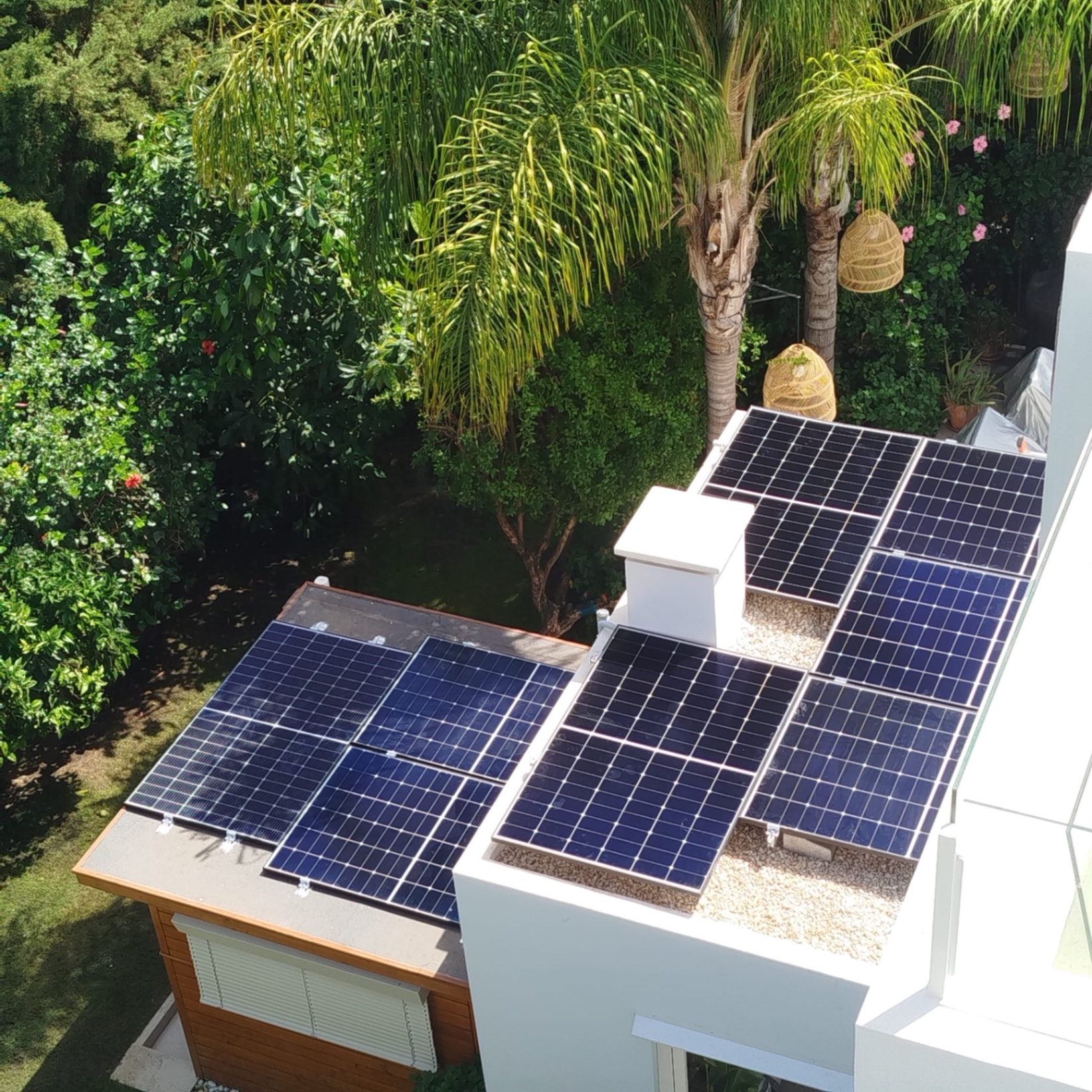 Solar panels spread over several roof levels of a villa with trees nearby