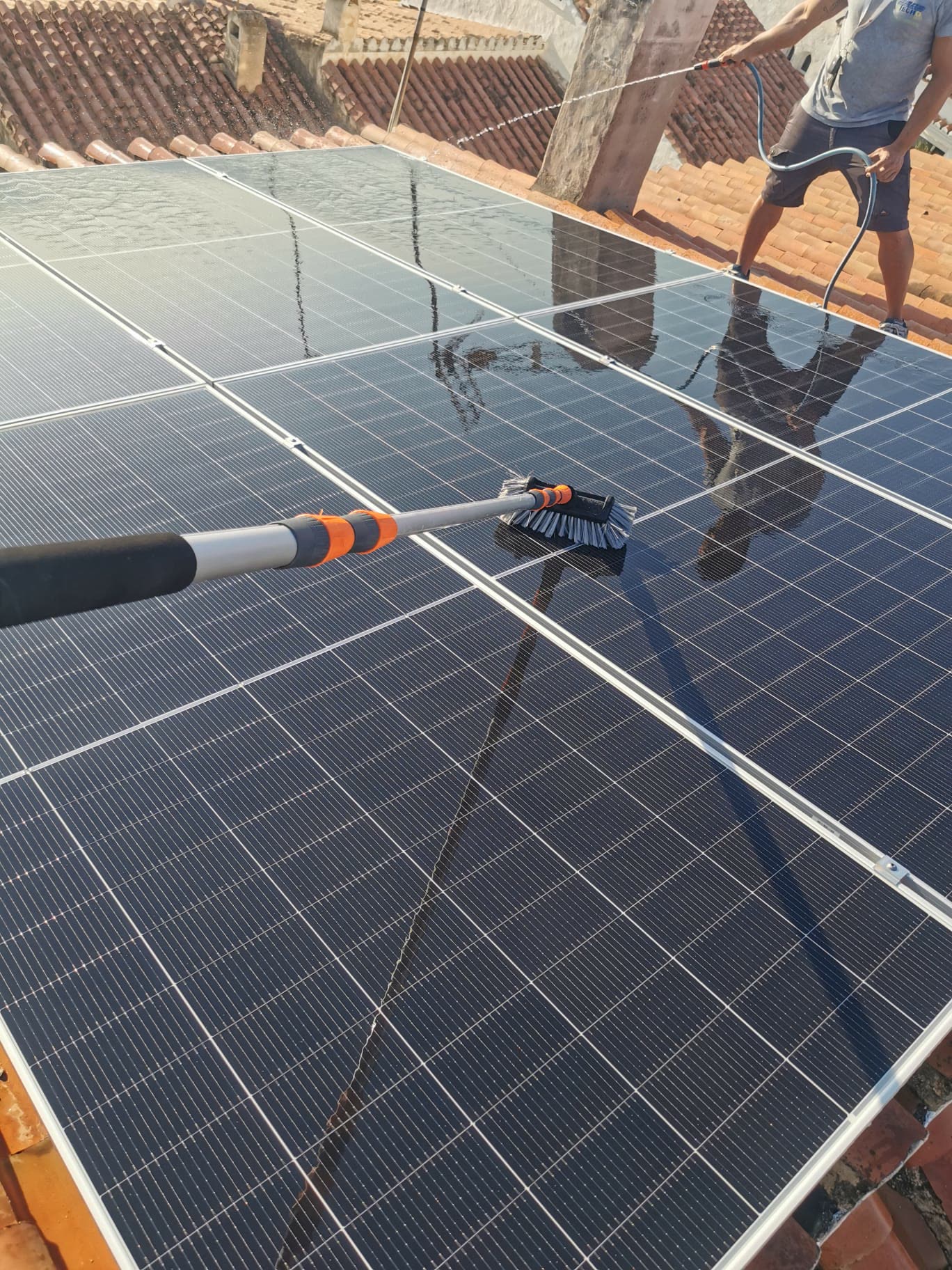 Mi Techo Solar technician cleaning solar panels on a roof on the Costa del Sol